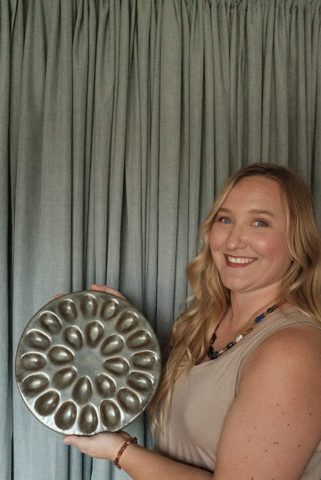 Kelly Devine smiling, holding one of her hand-built deviled-egg plates