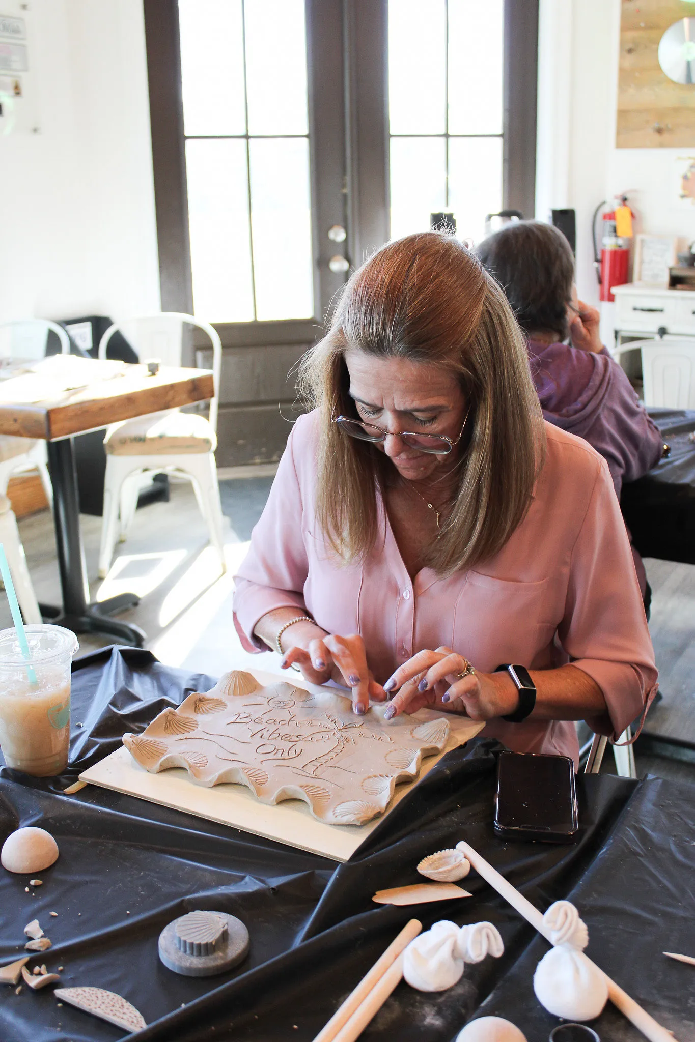 A student carving a beach design into a clay tray at a Devine Perks class