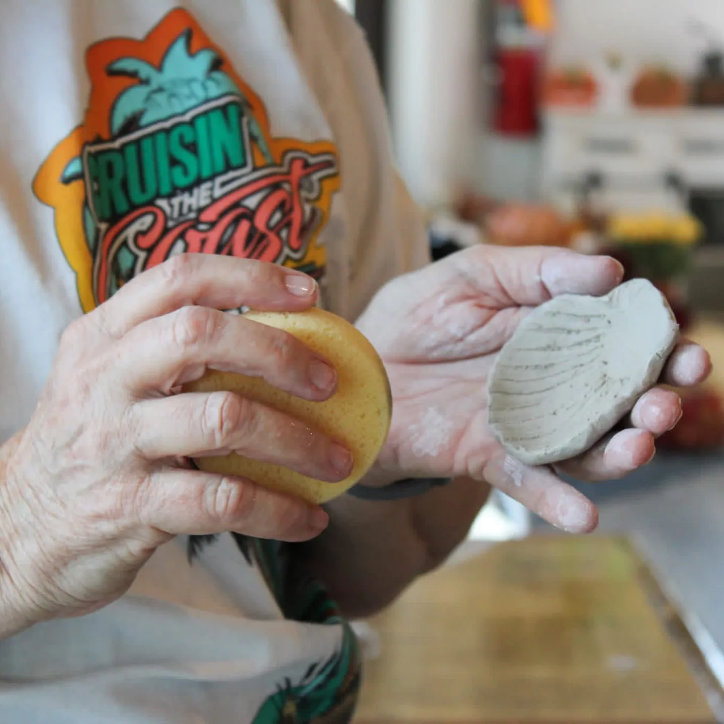 Smoothing a hand-pressed clay shell dish with a sponge